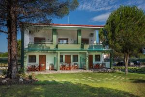 a large house with a yard and trees at Alexandros Hotel Apartments in Vourvourou