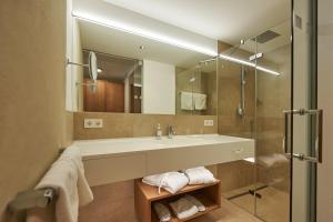 uma casa de banho com um lavatório e uma cabina de duche em vidro. em Après Post Hotel em Stuben am Arlberg