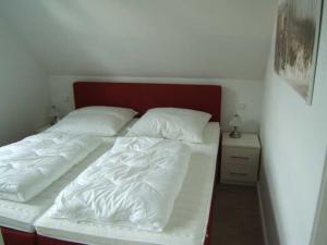 Bett mit zwei weißen Laken und einem roten Kopfteil in der Unterkunft PIRATENNEST 2 in Zingst