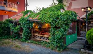 a building covered in ivy next to a building at Kalypso Hotel in Primorsko