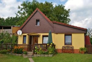 ein gelbes Haus mit einem Zaun und einem grünen Regenschirm in der Unterkunft Ferienhaus Schaffrath in Ehrenberg