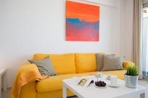 a yellow couch in a living room with a table at Apartments Cullera Beach in Cullera