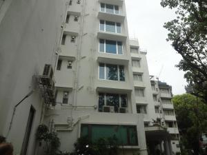 a tall white building with windows and stairs on it at Hiltop Hotel in Mumbai