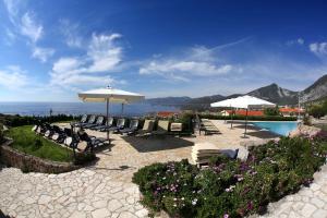 um pátio com cadeiras e guarda-sóis e uma piscina em Hotel Villa Gustui Maris em Cala Gonone