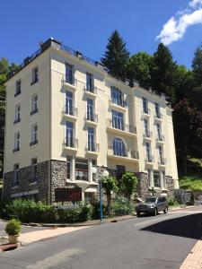 un grand bâtiment blanc sur le côté d'une rue dans l'établissement Le Pavillon, à La Bourboule