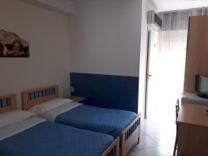 a bedroom with two beds and a television in it at B&B Brezza Marina & Ristorante Shoreline in Pozzallo