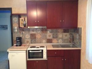 a kitchen with brown cabinets and a white stove top oven at Mairi Lina Studios in Kala Nera
