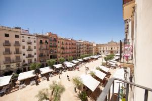 a city street with tables and white umbrellas and buildings at El Faro Apartaments in Tarragona