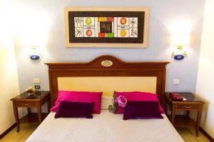 a bedroom with a large bed with pink pillows at Hotel Riva Del Sole in Cefalù