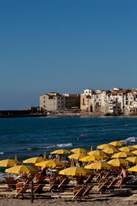 a bunch of chairs with umbrellas on a beach at Hotel Riva Del Sole in Cefalù