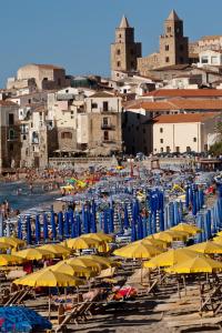 a bunch of umbrellas and chairs on a beach at Hotel Riva Del Sole in Cefalù