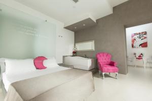 una camera con letto, lavandino e sedia rosa di Hotel Nunù a Napoli