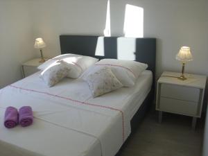 a bedroom with a white bed with purple slippers on it at Open Hus in Krvavica +60 photos