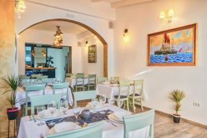 ein Restaurant mit weißen Tischen und Stühlen und einem Gemälde in der Unterkunft Hotel Boutique Natka in Rovinj