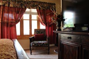 a bedroom with a bed and a chair and a window at All Seasons Inn in Eureka Springs