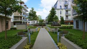a walkway through a park with benches and apartment buildings at Apartament Magdalena in Świnoujście