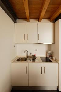 uma cozinha com armários brancos e um lavatório em Antiga Casa do Boi em Viseu
