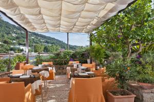 um restaurante com mesas e cadeiras sob um grande guarda-sol em Hotel Senaria em Anacapri