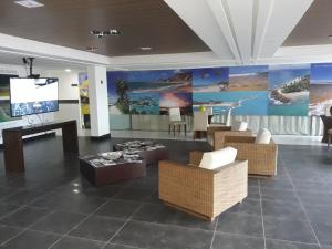 eine Lobby mit Stühlen und einem Flachbild-TV in der Unterkunft Mar do Cabo Branco Residence in João Pessoa