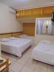 a room with two beds and a window at Hotel Makarena in Três Corações