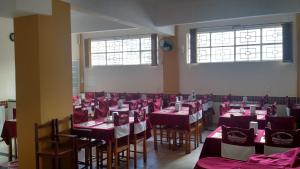 a dining room with red and white tables and chairs at Hotel Makarena in Três Corações