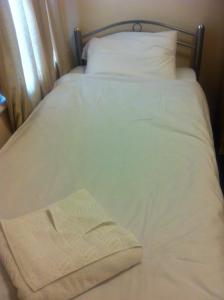 a bed with white sheets and a book on it at London Olympus Hotel in London