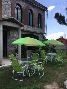 a group of tables and chairs with green umbrellas at Hotel Coatlicue in San Juan Teotihuacán