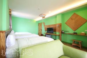 a green room with two beds and a couch at Taitung Sea Wall Homestay in Taitung City