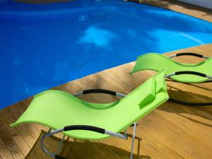 a green chair next to a swimming pool at La Tonnelle Guest House in Trou aux Biches