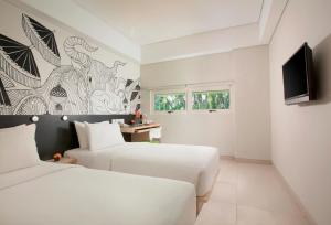 two beds in a white room with a tv at Grandmas Plus Hotel Airport in Kuta