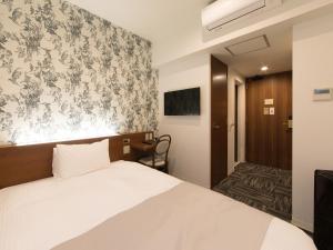 a bedroom with a white bed and a floral wallpaper at S.Training Center Hotel Osaka in Osaka