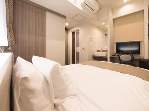 a bedroom with a white bed with white pillows at S.Training Center Hotel Osaka in Osaka