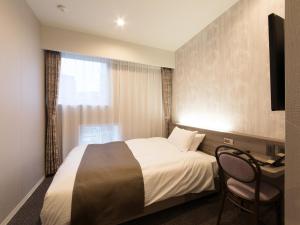 a hotel room with a bed and a desk and a window at S.Training Center Hotel Osaka in Osaka