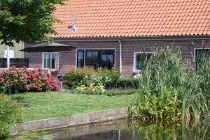 una casa con sombrilla junto a un estanque en Gastenverblijf De Natureluur en Noorden