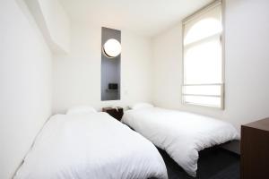 2 camas en una habitación blanca con ventana en Kurashiki Global Hotel, en Kurashiki