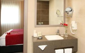 a hotel bathroom with a sink and a bed at Golden Tulip Kassel Hotel Reiss in Kassel