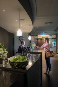 a woman standing in a kitchen preparing food at Novotel Melbourne On Collins in Melbourne