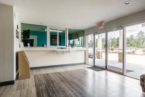 a large room with a kitchen with a counter and sliding glass doors at Scottish Inn and Suites Tomball in Tomball