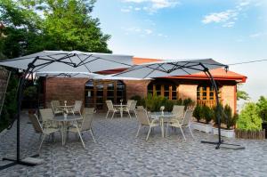 een patio met tafels, stoelen en parasols bij Hotel Brigitte in Sighnaghi