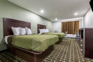 a hotel room with two beds and a television at Scottish Inn and Suites Tomball in Tomball