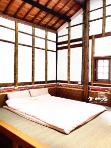 ein großes Bett in einem Zimmer mit Fenstern in der Unterkunft Bamboo House in Zhushan