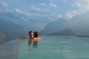 a man and woman swimming in the water in the mountains at Topas Ecolodge in Sapa
