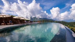 a swimming pool with umbrellas and people sitting around it at Topas Ecolodge in Sapa