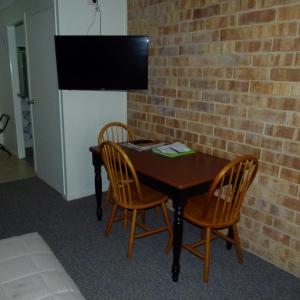 a table with two chairs and a television on a brick wall at Lismore Wilson Motel in Lismore
