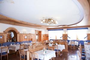 ein Esszimmer mit Tischen, Stühlen und einem Kronleuchter in der Unterkunft Hotel Jolanda in San Martino di Castrozza