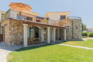 a stone house with a balcony with an umbrella at Country Domos Tramentu in Ozieri