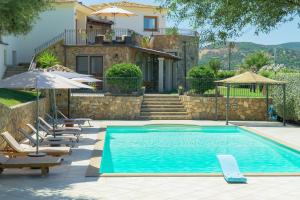a pool with chairs and umbrellas next to a house at Country Domos Tramentu in Ozieri
