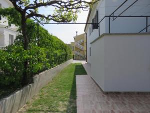 an alley between two buildings with green grass at Apartments Čubranić in Baška