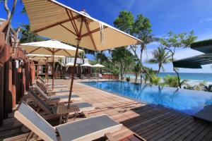 a pool with chairs and umbrellas next to the ocean at Ao Prao Resort in Ko Samed