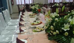 einen langen Tisch mit Weingläsern und Blumen darauf in der Unterkunft Hotel Satelit Kumanovo in Kumanovo